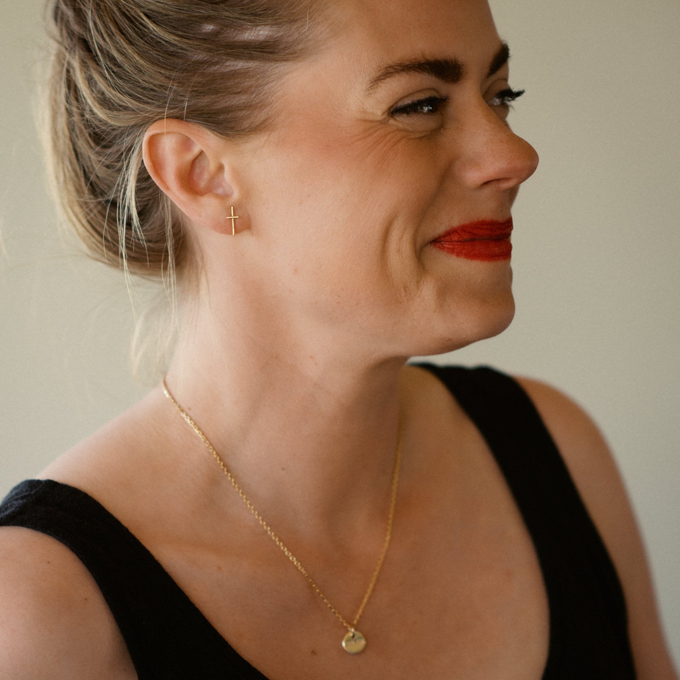 Woman wearing a 18K gold necklace with a small pendant, against a neutral background
