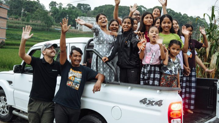 Group of people with raised hands in front of a white 4x4 vehicle on a road. love and hope