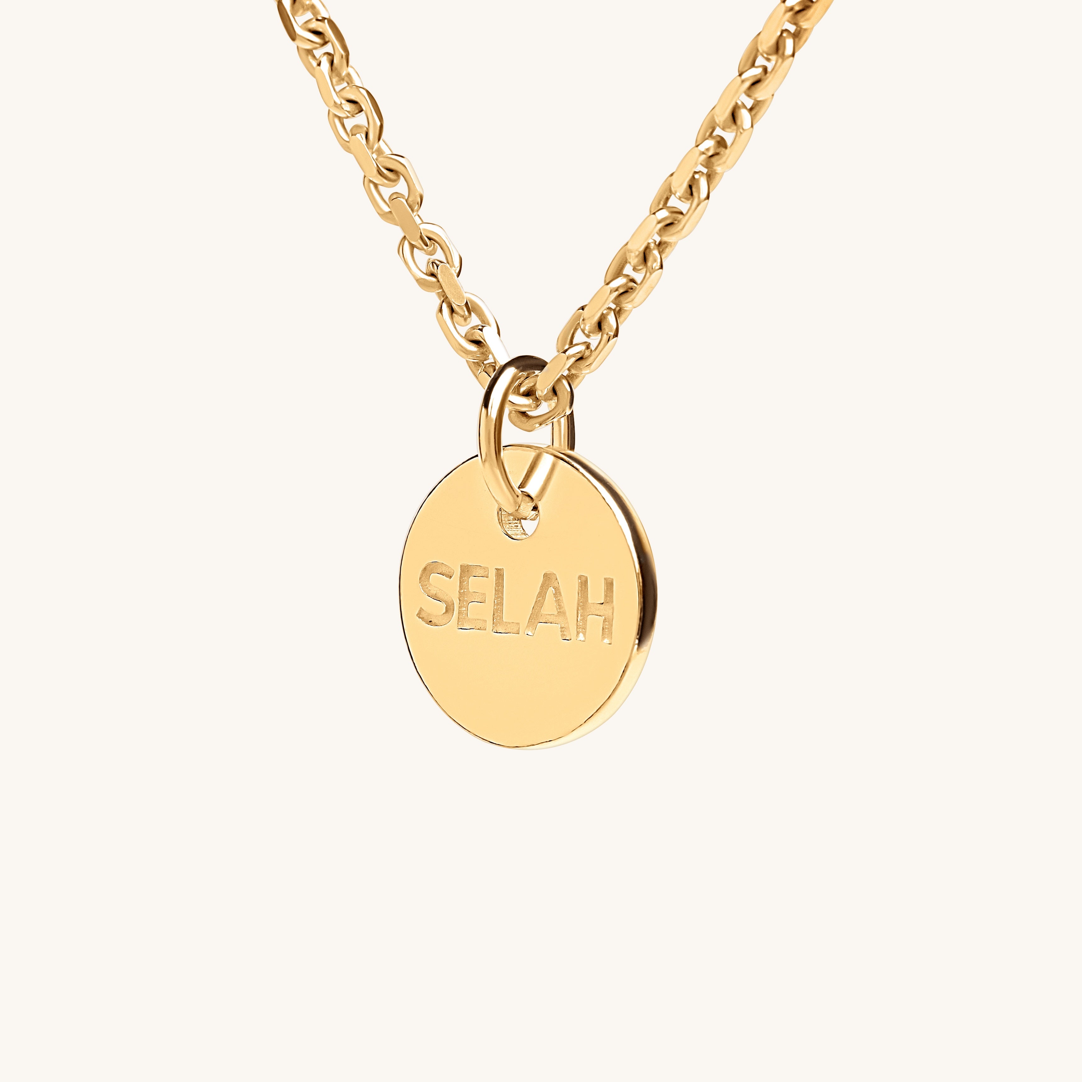 PS46 Jewelry Selah 18K gold necklace with 'SELAH' pendant, angled side view, displayed on an off-white background.