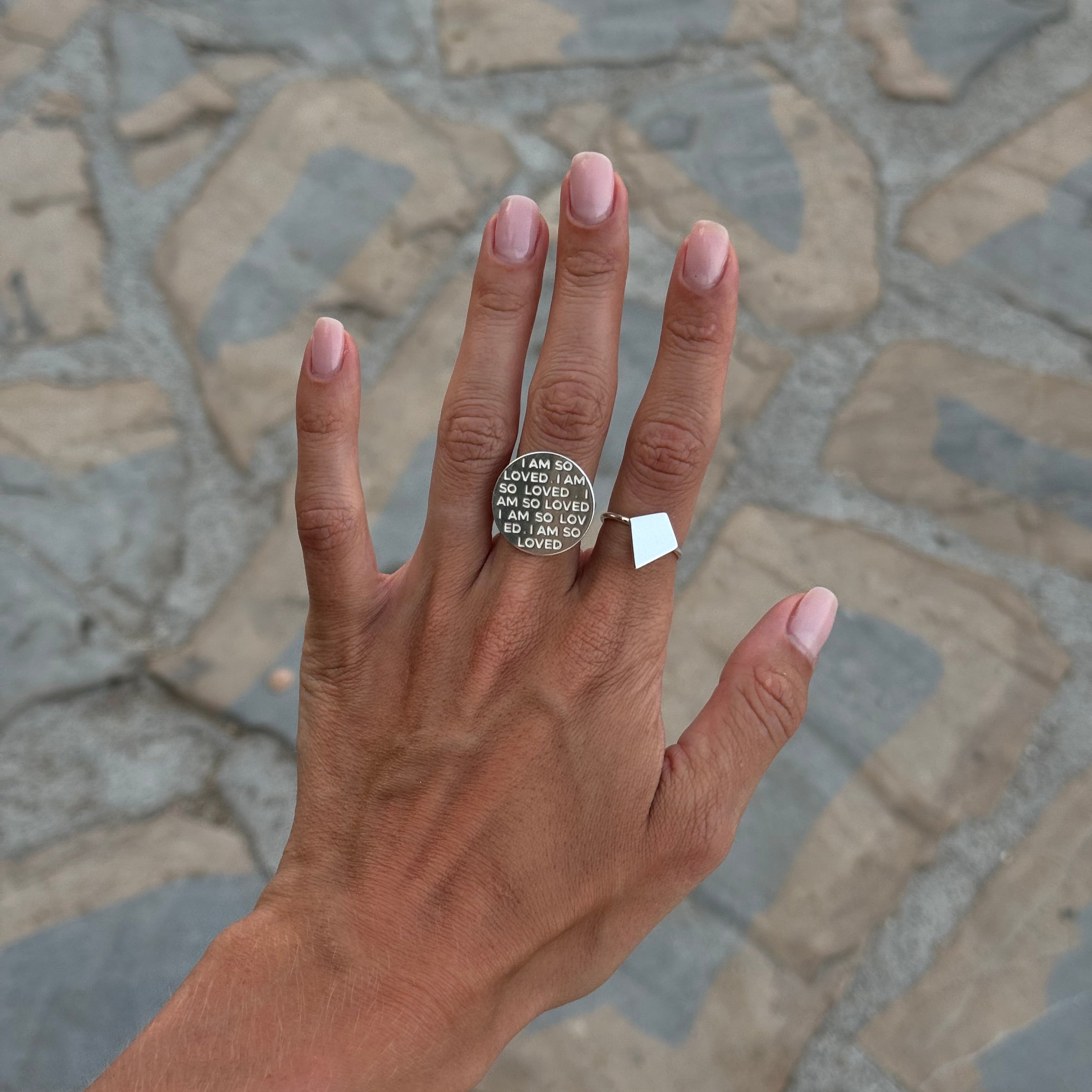 Close-up of woman's hand wearing Shield of Faith Ring and I Am So Loved Ring