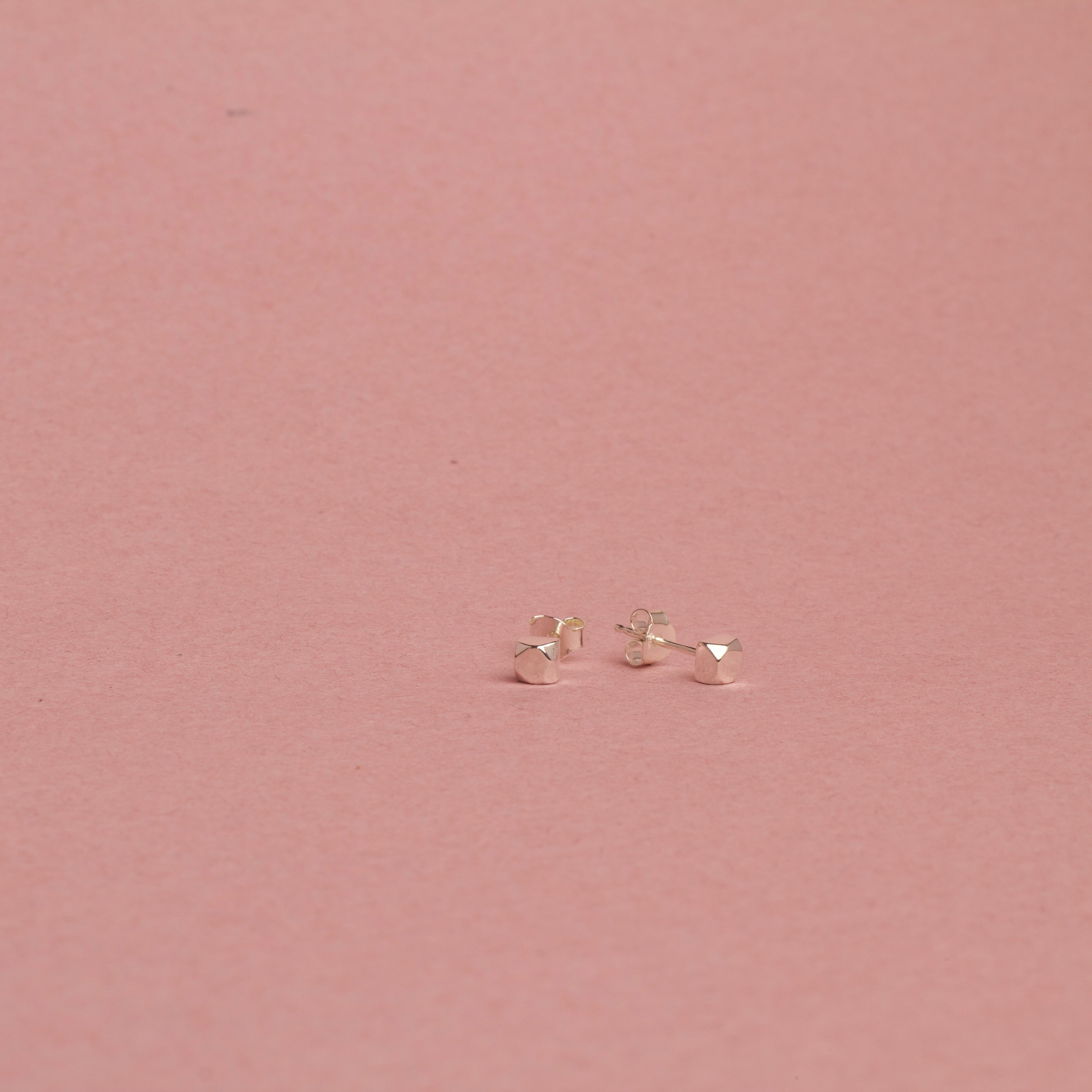 white gold earrings on a pink background