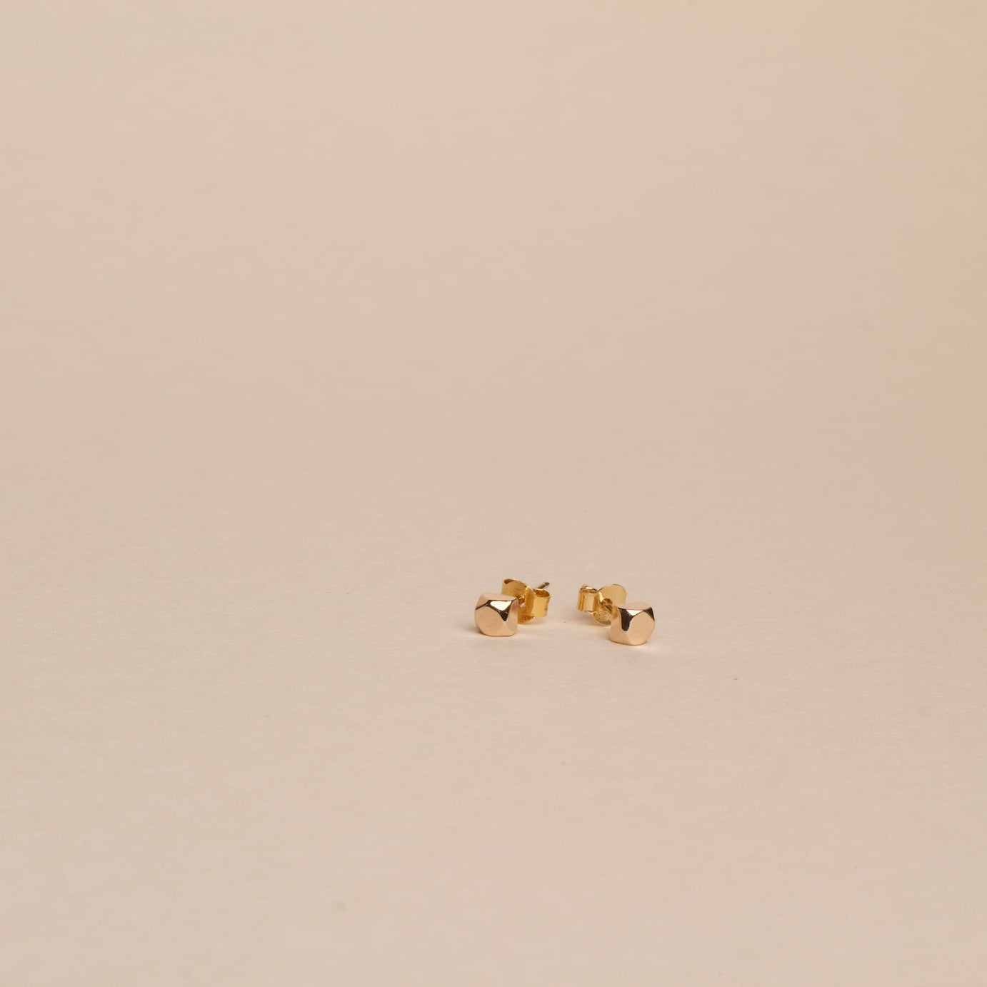Gold earrings on a beige background