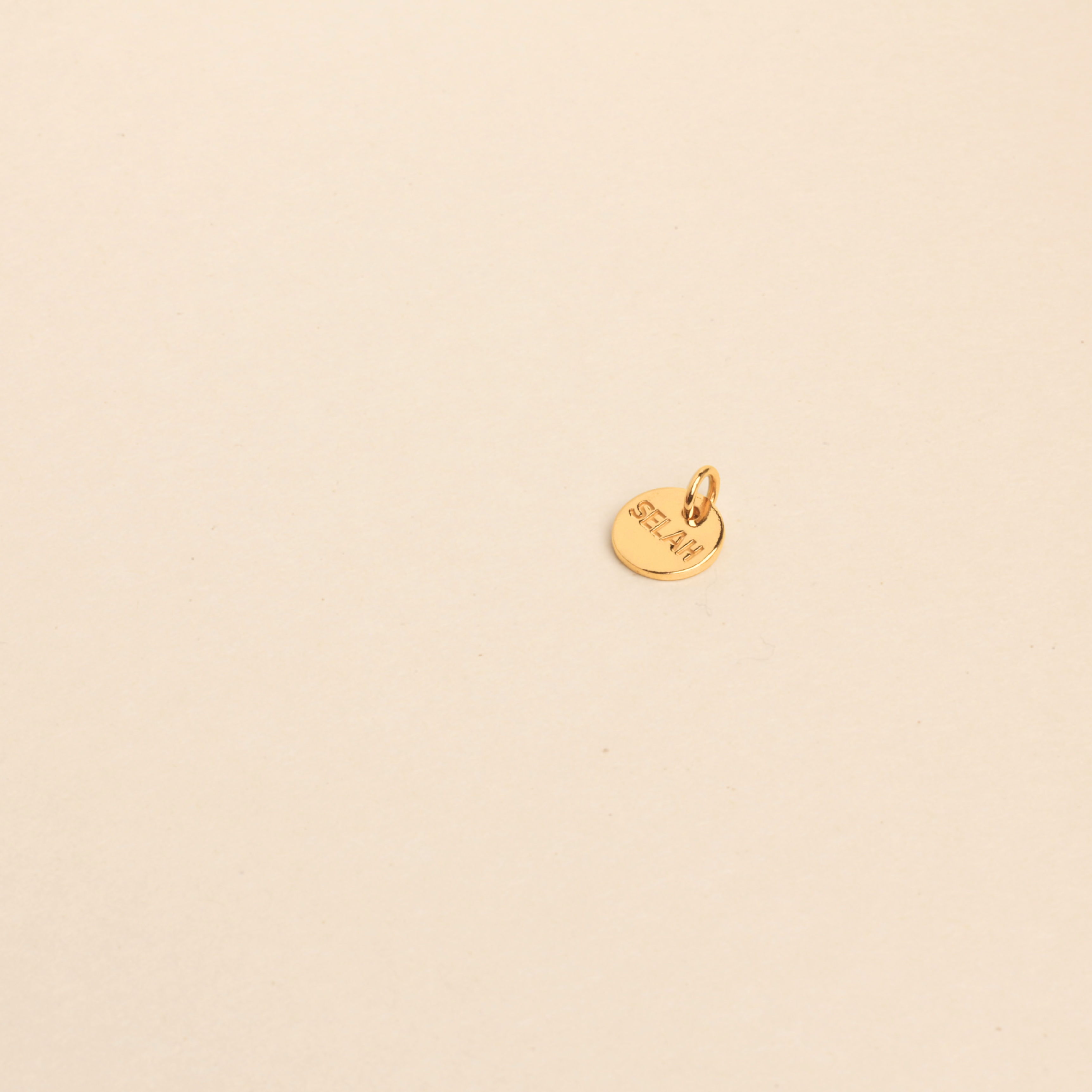 PS46 Jewelry Selah 18K gold pendant lying on a beige background.