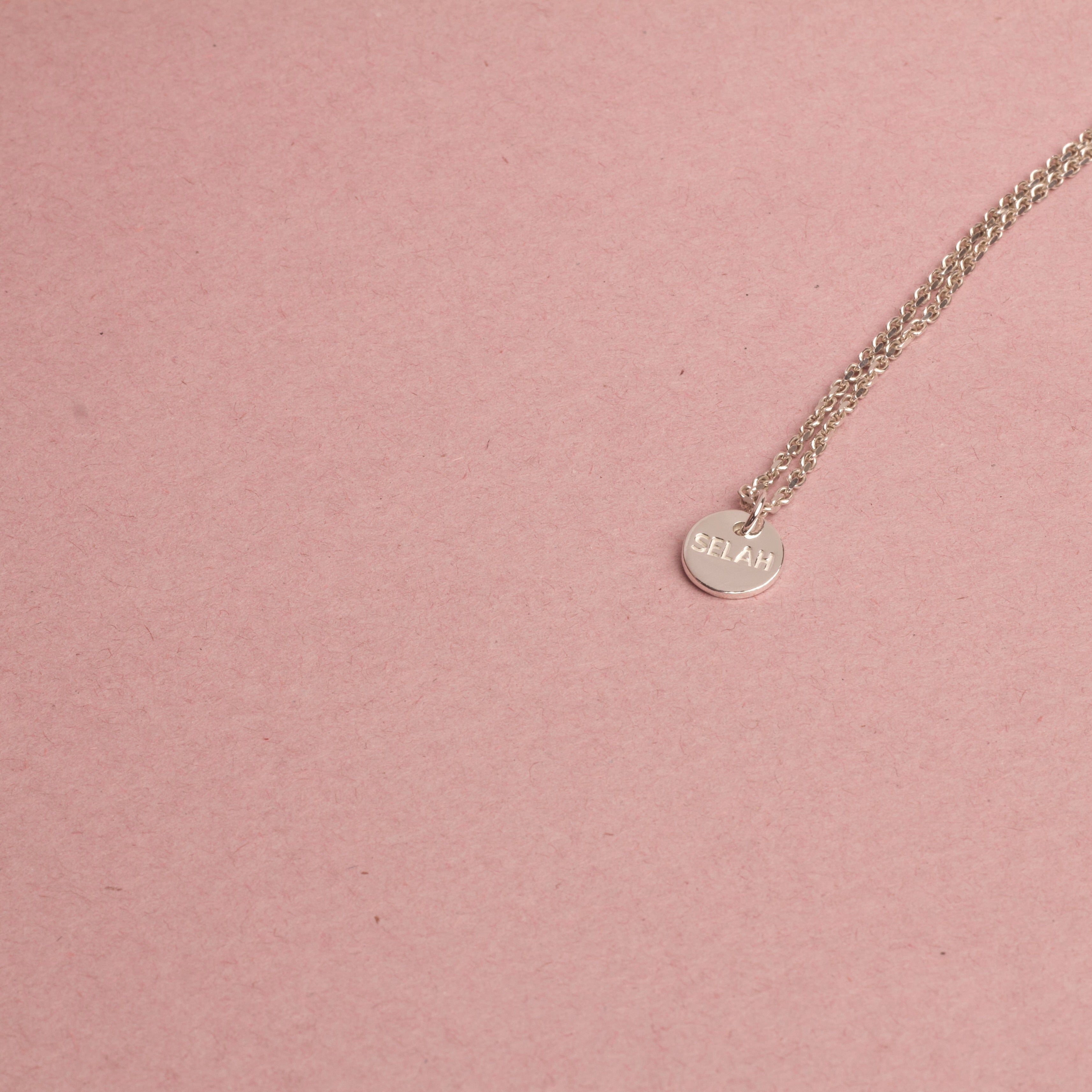 PS46 Jewelry Selah silver necklace on a pink background.