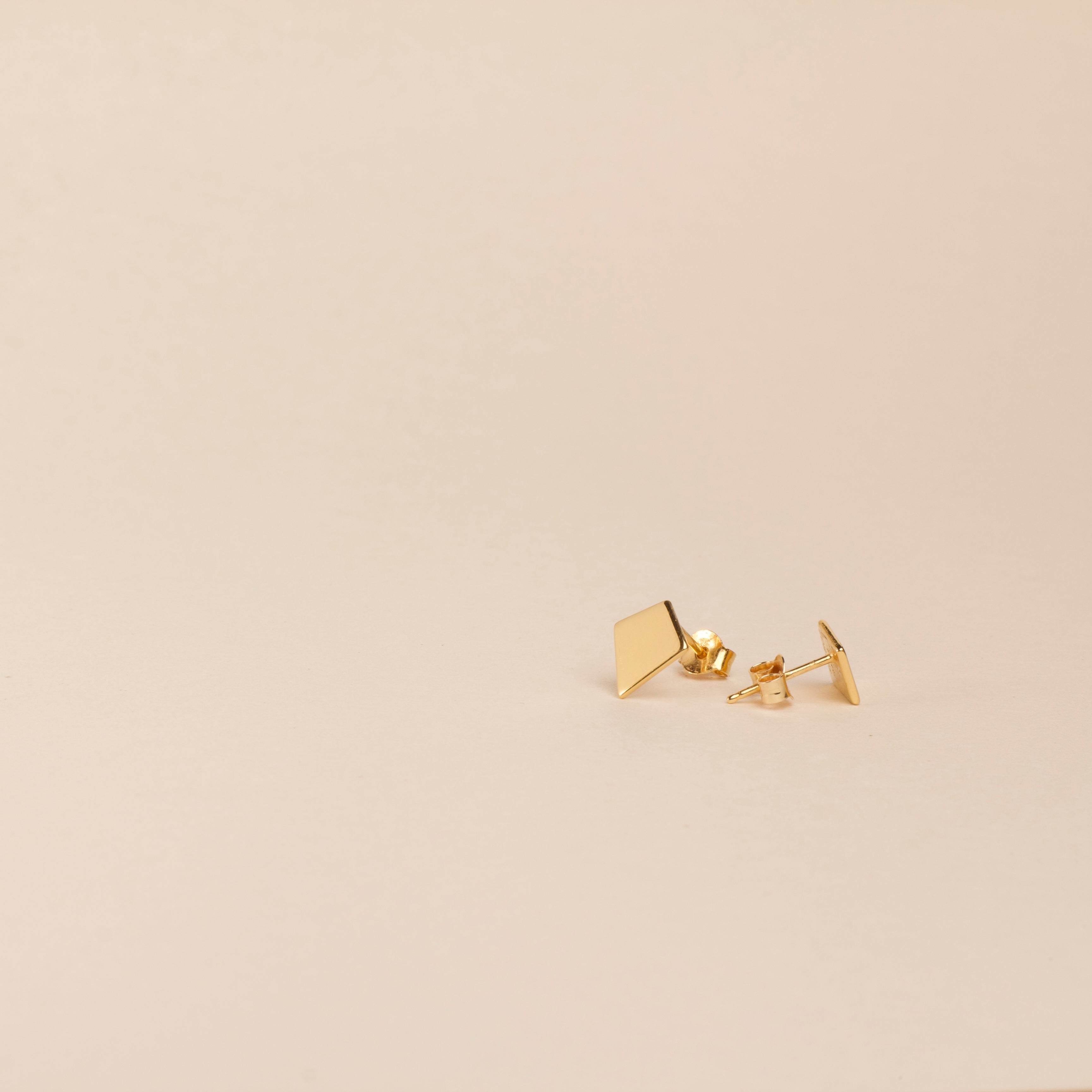 18K Gold earrings on a beige background, shield of faith, stud