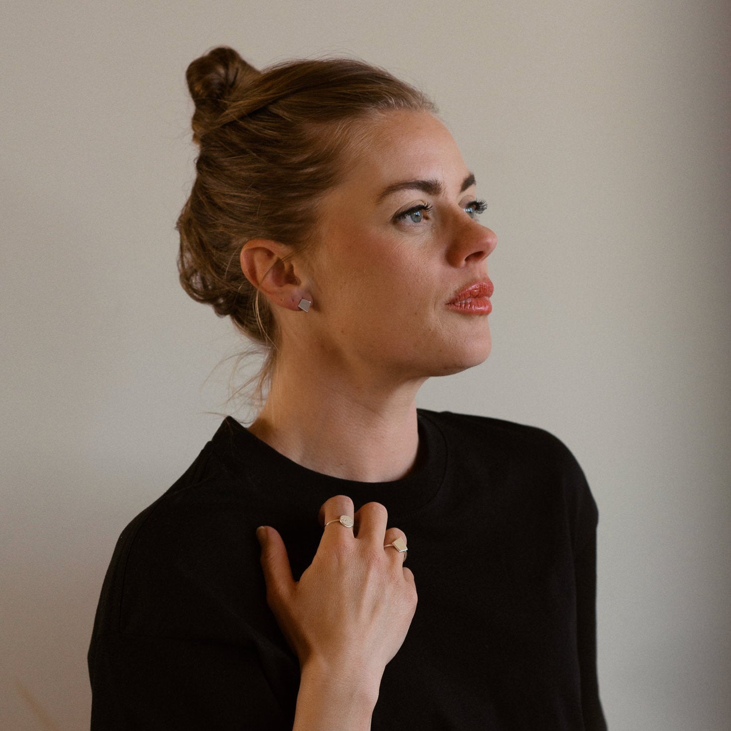 Woman wearing a black top against a plain background, 18K white gold, shield of faith, stud