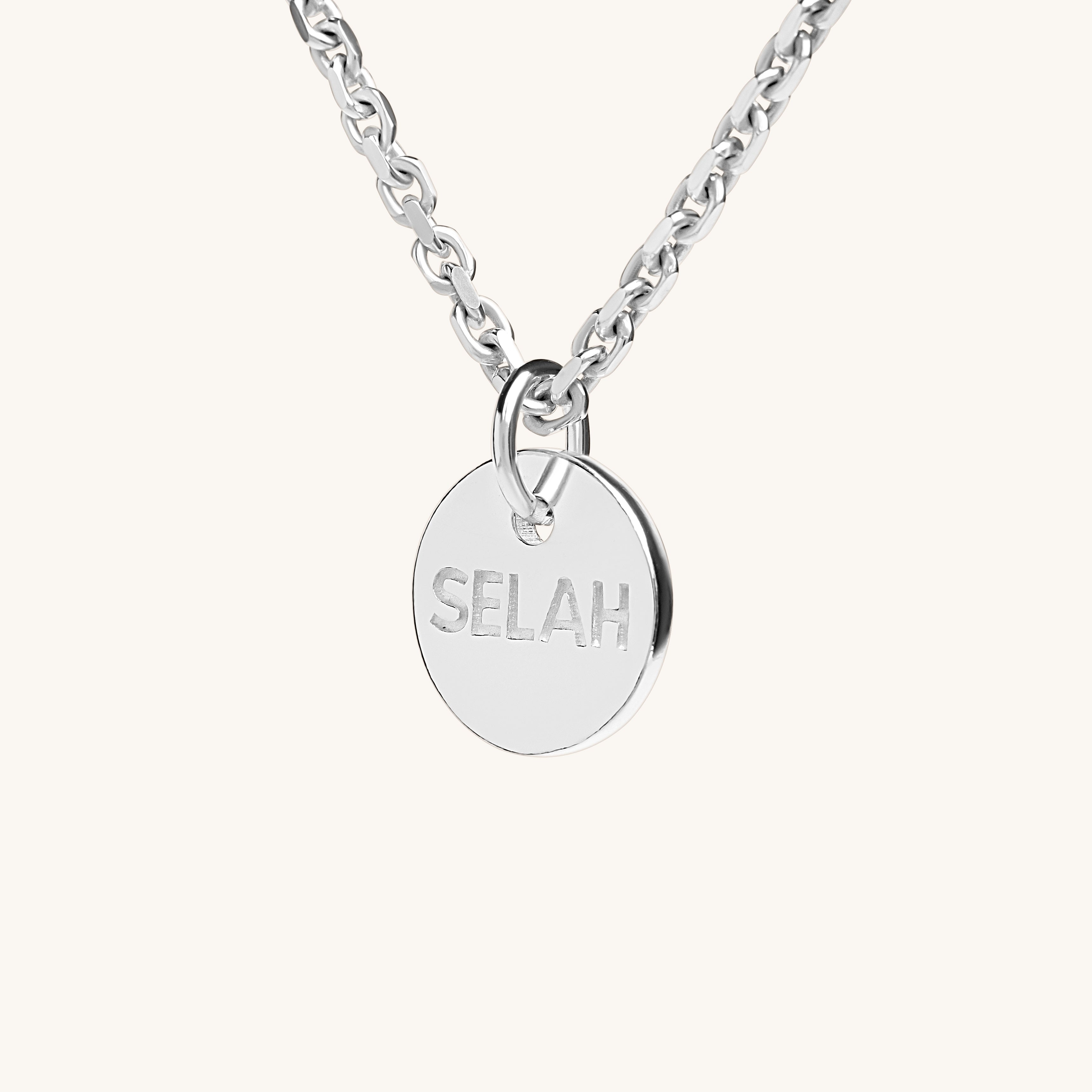 PS46 Jewelry Selah silver necklace with 'SELAH' pendant angled side view displayed on an off-white background.