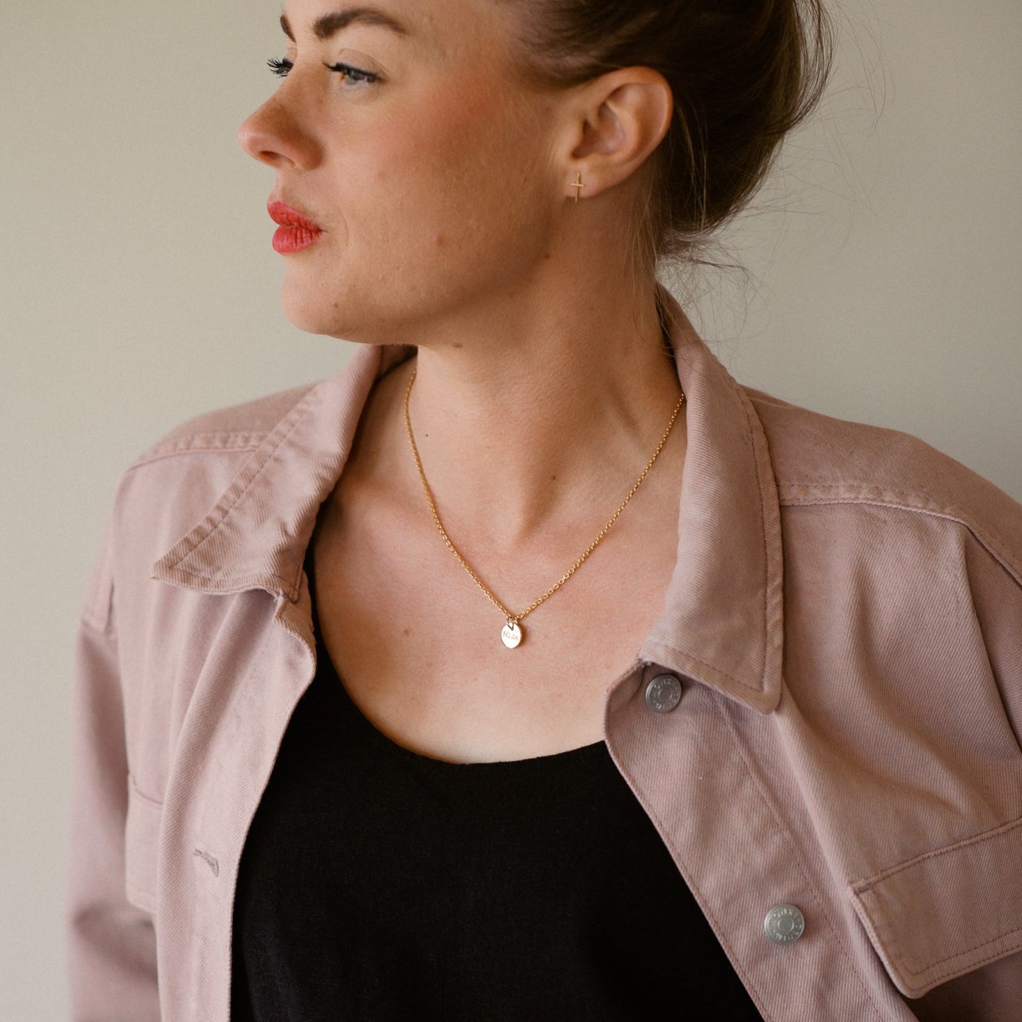 Woman wearing a pink jacket over a black top with a neutral background