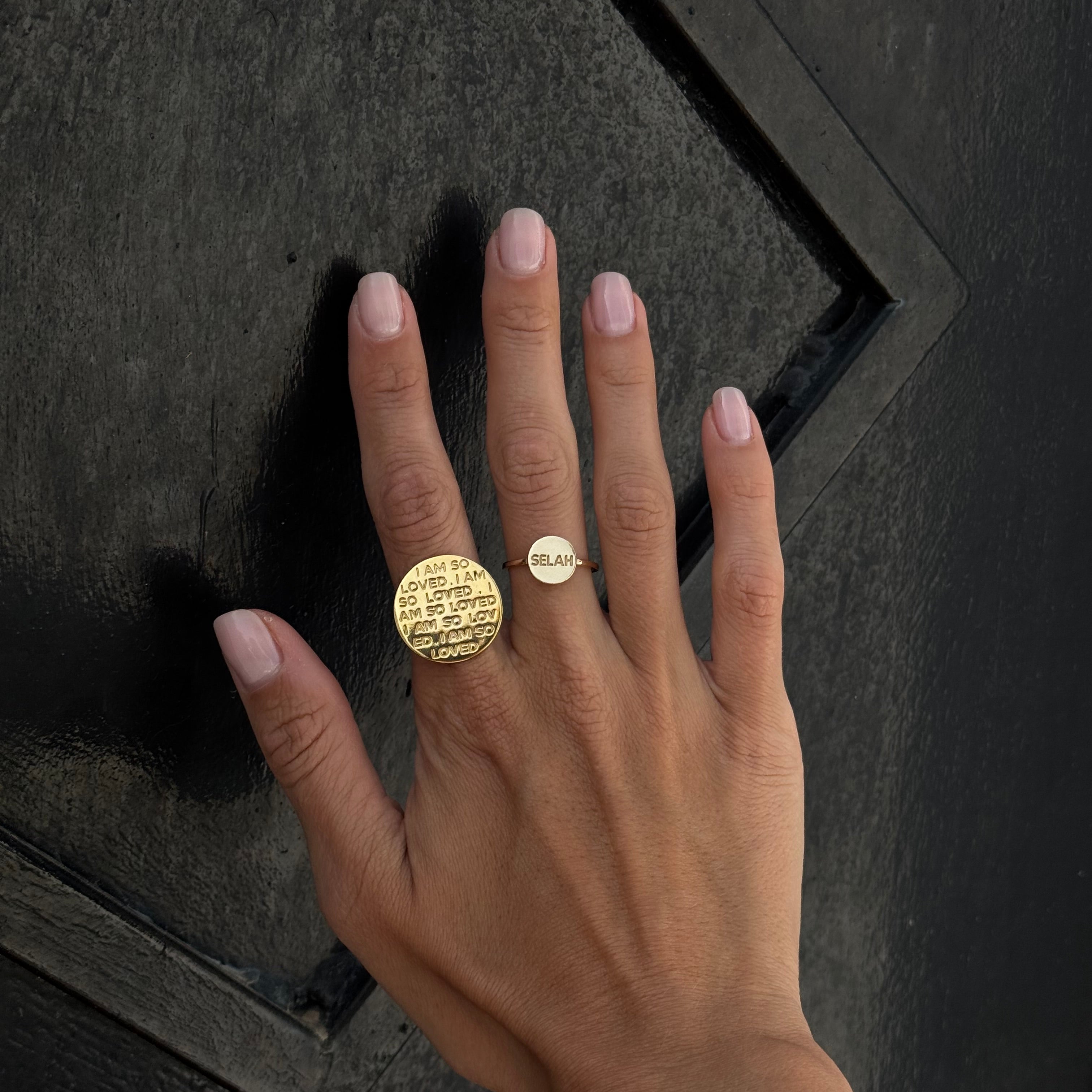 Hand wearing a gold ring on a dark textured surface